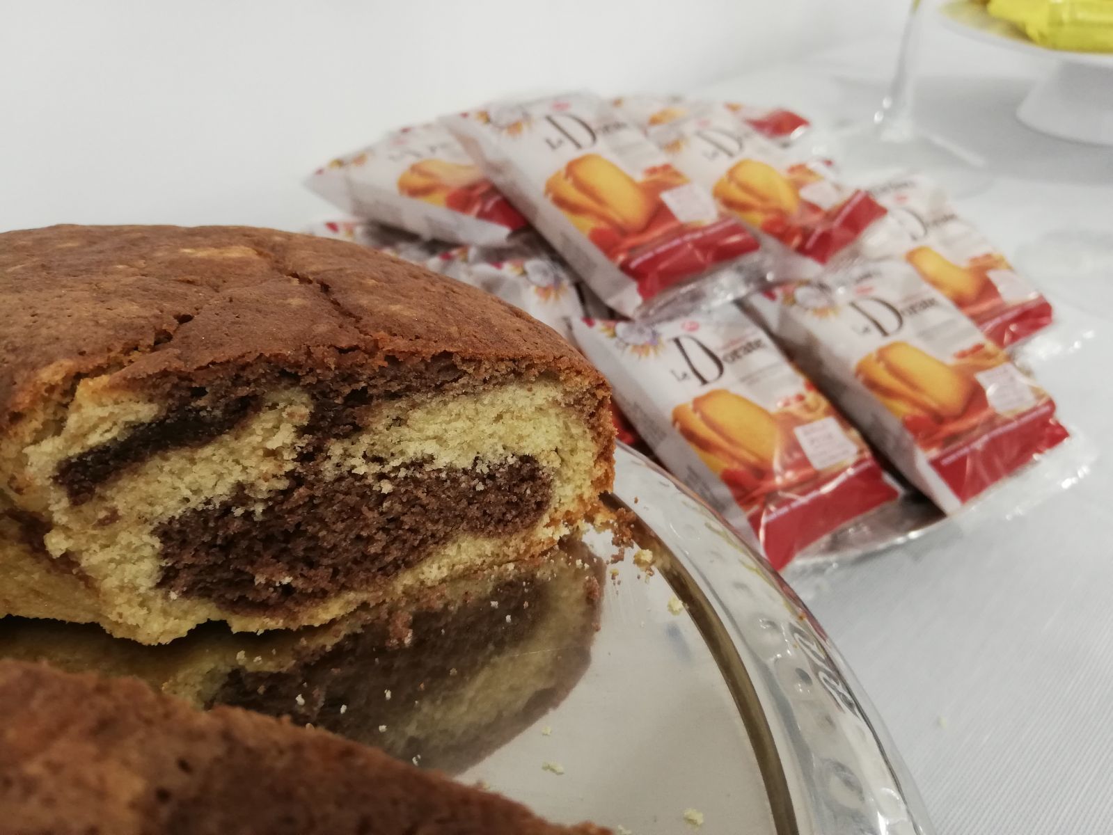 Ein Stück Kuchen mit Schichten aus Schokolade und Sahne, im Hintergrund Päckchen mit La Dorne Schokoladenkeksen.