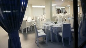 A well-lit dining area with round tables and white chairs, featuring a modern ceiling design and large windows. - Domus Grand Hotel (Rende)