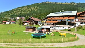 A rural hotel with a green lawn, a trampoline, and a yellow cow statue. - Hotel Zum Senn (Bad Hindelang)