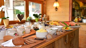A buffet setup with various food items and a heart-shaped decoration on the counter. - Hotel Zum Senn (Bad Hindelang)