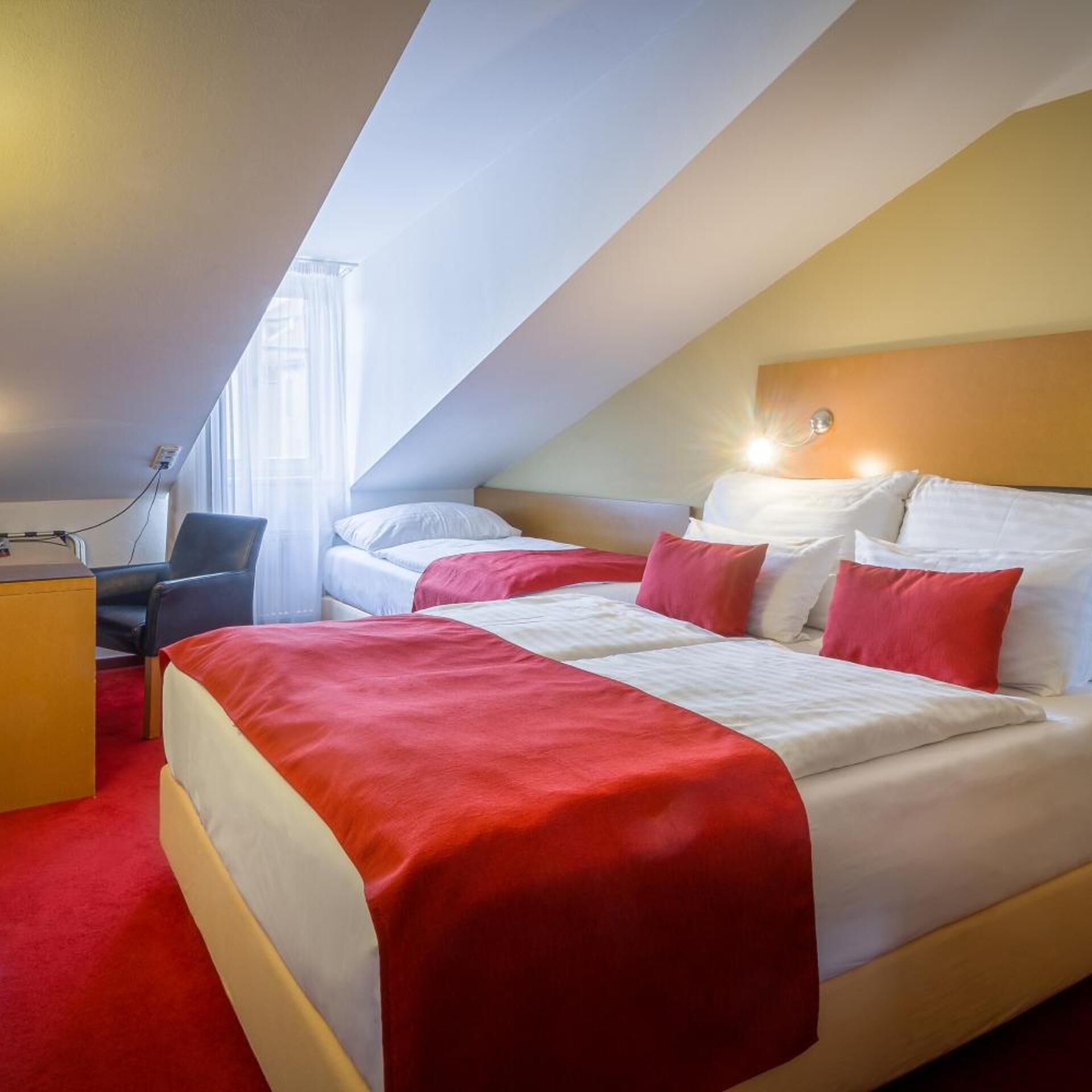 Une chambre d’hôtel avec un lit, un bureau et une chaise.