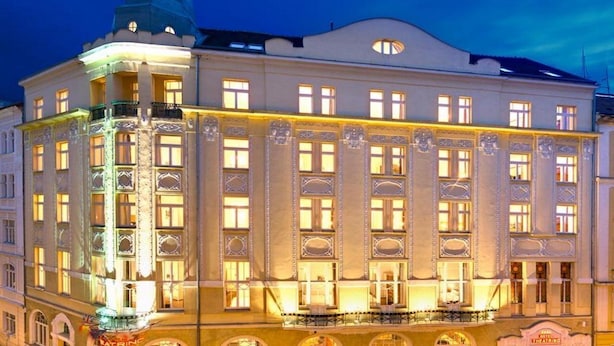 Un edificio histórico con detalles arquitectónicos ornamentales, varios balcones y una imponente torre en esquina.