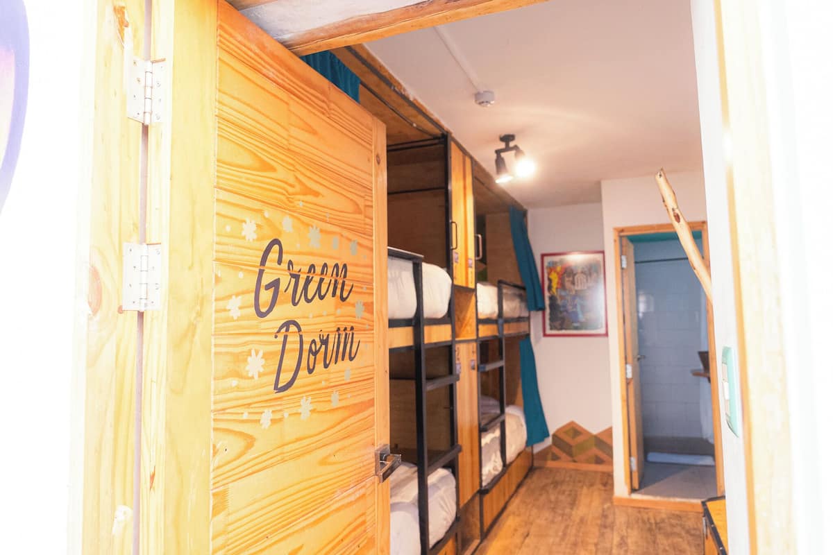 A wooden room with bunk beds labeled "Green Dorm."