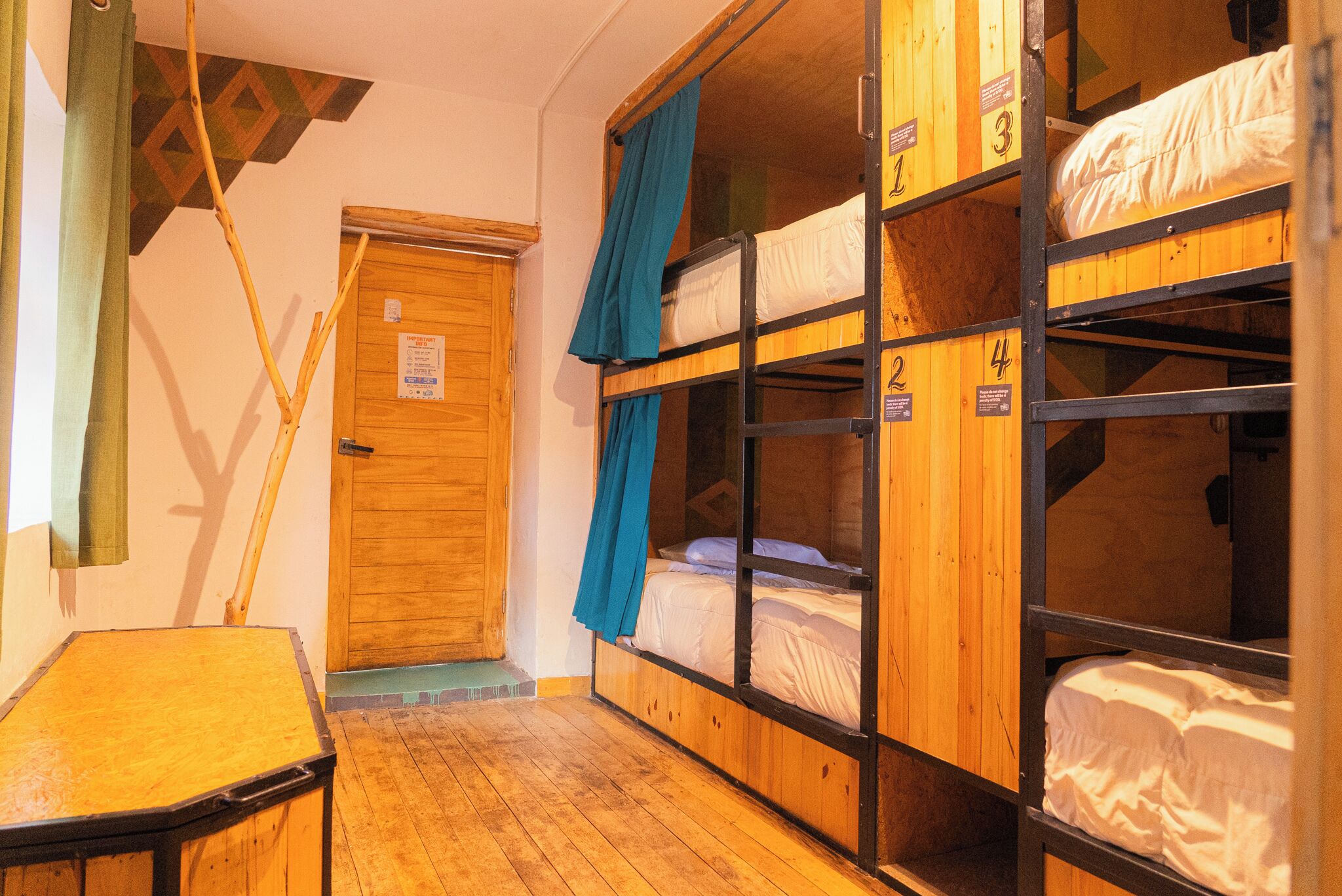 A dormitory-style room with bunk beds, wooden walls, and a small table.