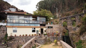 Un bâtiment en pierre avec une extension en verre, un escalier et un pont en pierre.