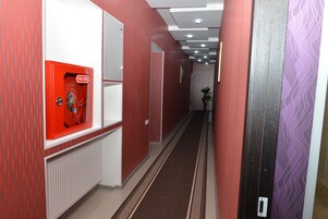 A hallway with a fire hose cabinet, patterned walls, and a radiator.
