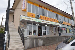 A hotel with a signboard, a staircase, and a parked car.