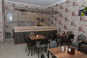 A dining area with a central bar, wooden tables, and chairs.