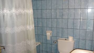 Un baño con azulejos azules, un inodoro, un lavabo y una cortina de ducha.