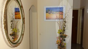 A hallway with a mirror, a painting, and a vase with flowers. - Hostal Terraferma (Algerri)