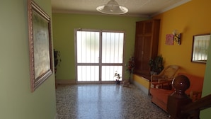 A spacious room with a large sliding glass door leading to a balcony, a wooden chair, and a small table with a plant. - Hostal Terraferma (Algerri)
