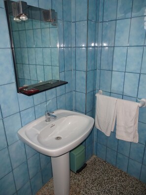 A bathroom with a white sink, blue-tiled walls, a mirror, and a towel rack. - Hostal Terraferma (Algerri)