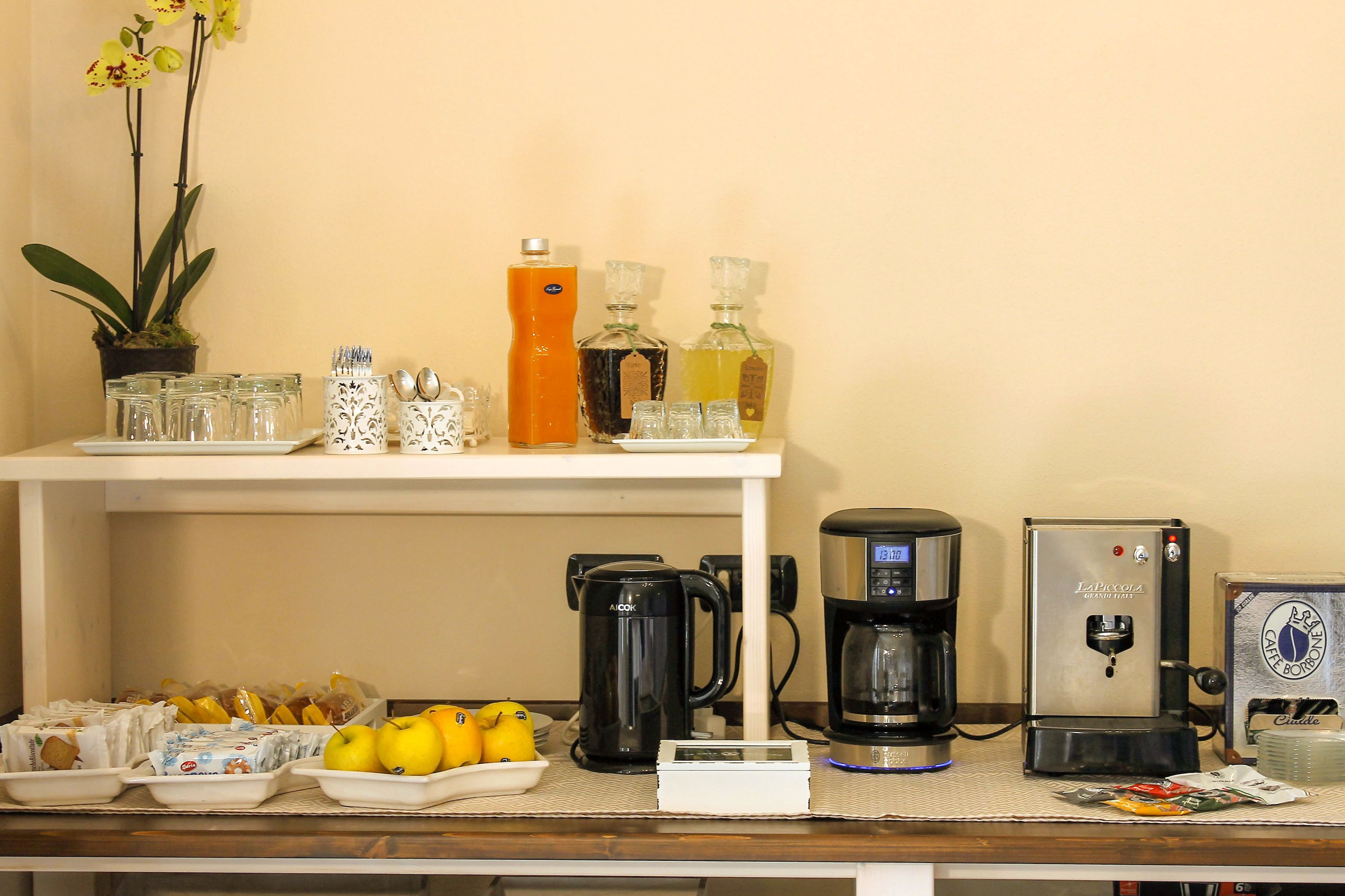 Un comptoir-buffet pour le petit-déjeuner, avec des machines à café, un distributeur d’eau et une variété d’aliments pour le petit-déjeuner, notamment des fruits et des viennoiseries.