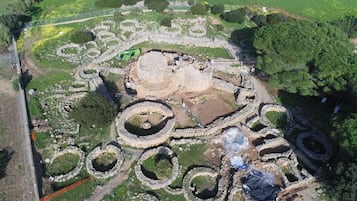 An aerial view of an archaeological site with multiple circular stone structures and a large central ruin.