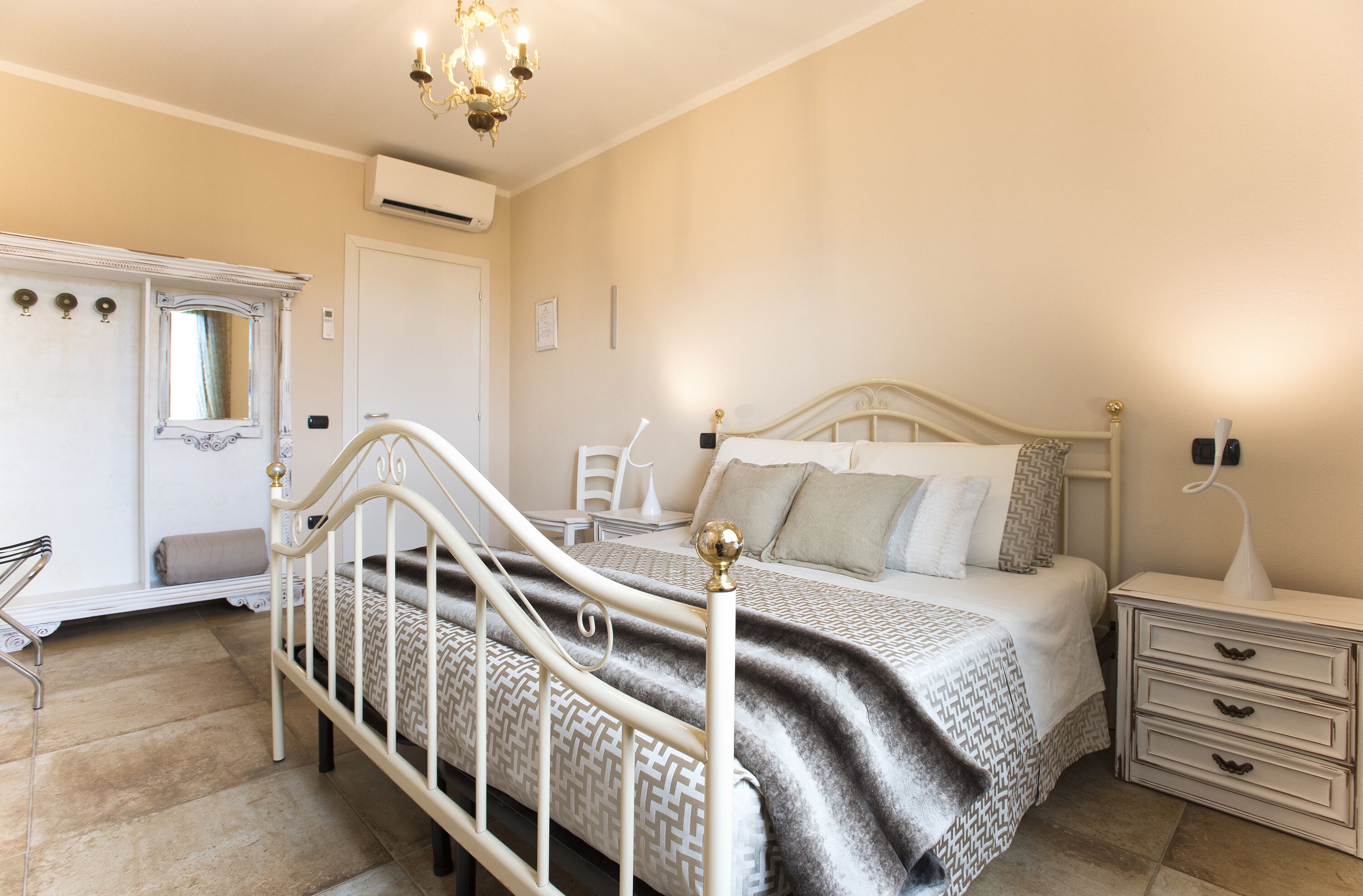 Une chambre à coucher comprenant un lit, une table de chevet, une commode, une coiffeuse et un lustre.