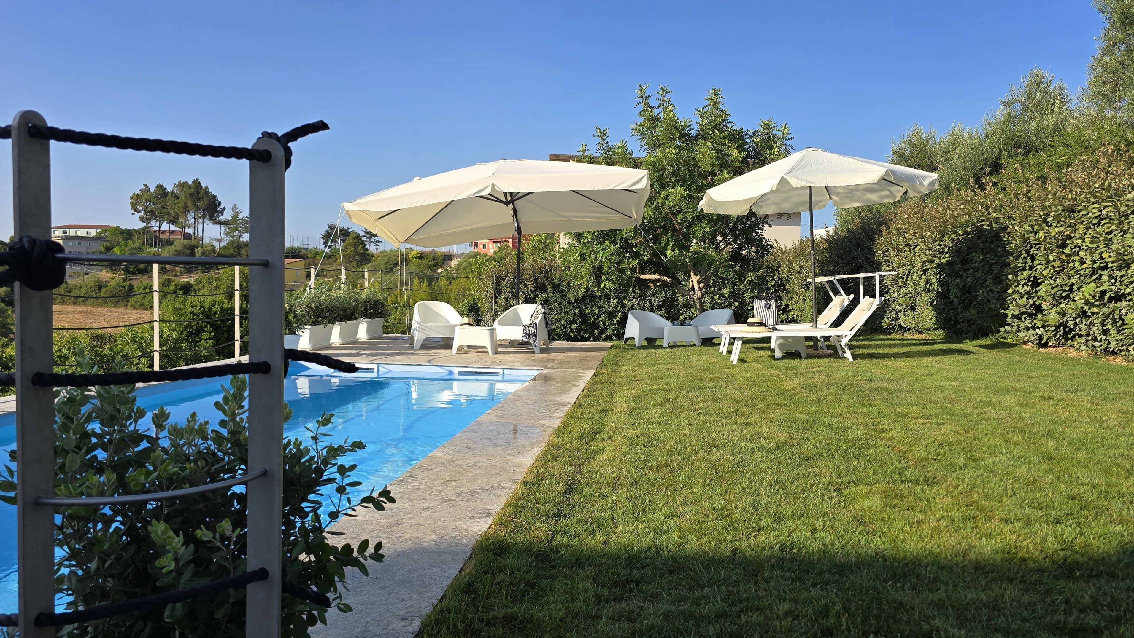 Une piscine entourée d’une terrasse, de chaises longues et de parasols.