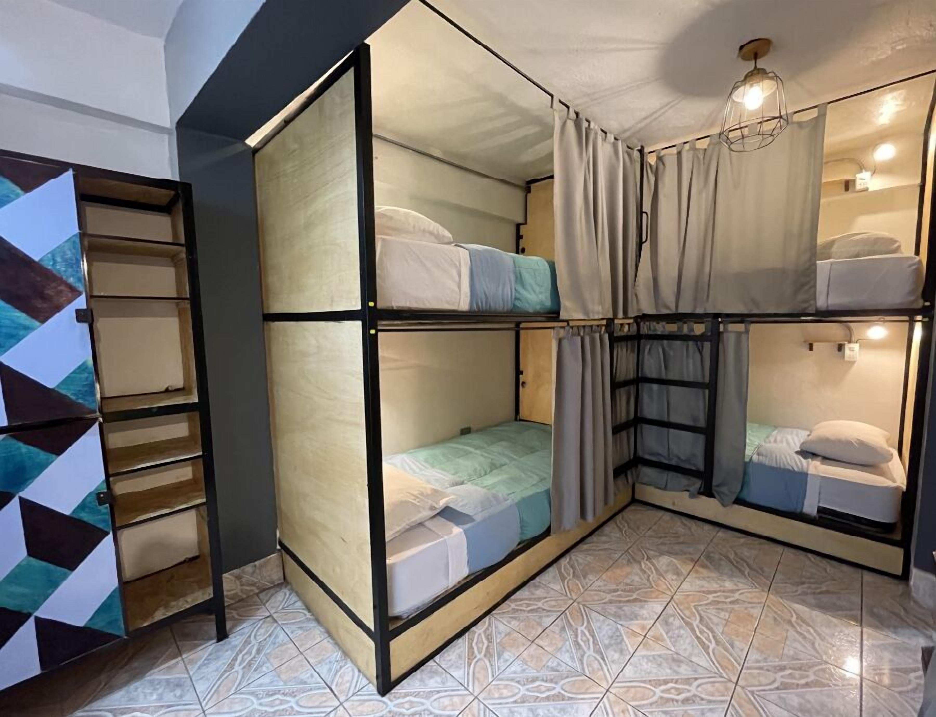 A compact, multi-level bunk bed room with a geometric-patterned wall and patterned floor tiles.