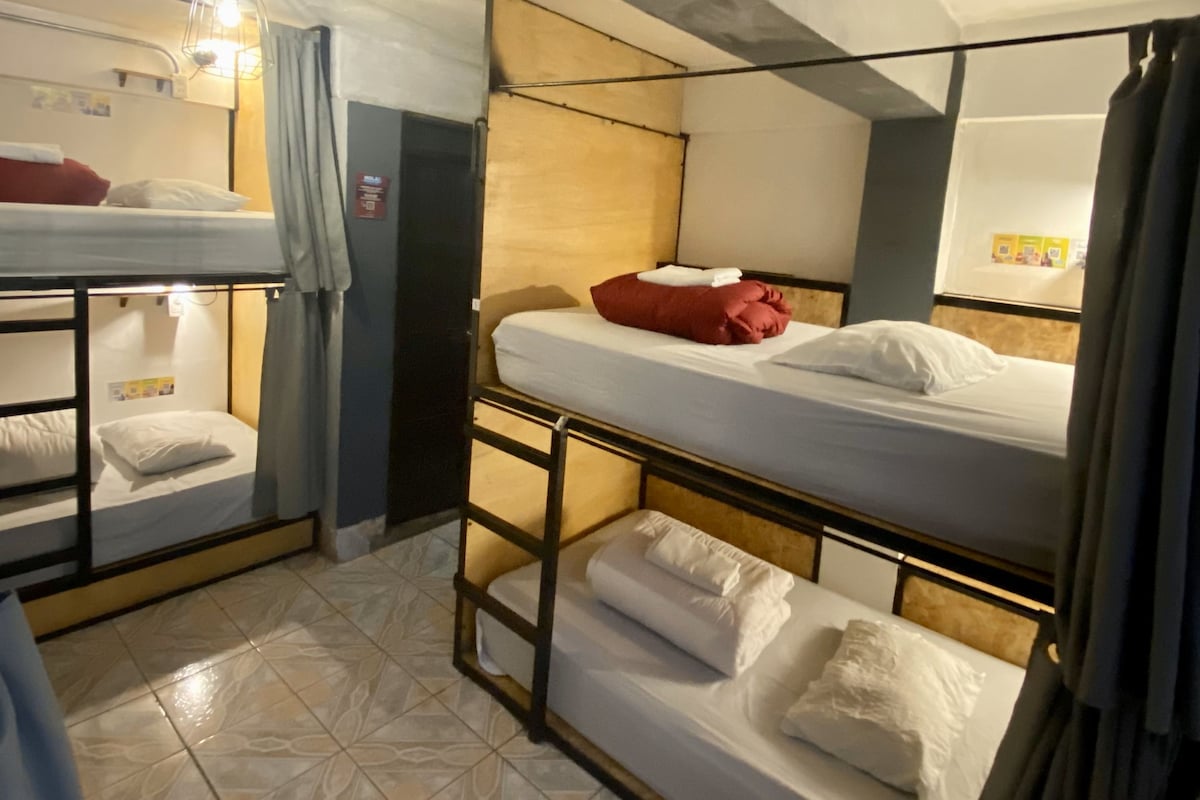 Un dormitorio con literas, un ventilador de techo y un estante con objetos.