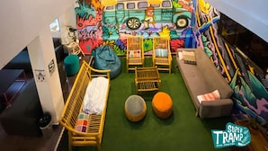 A vibrant room with a colorful mural, a small sofa, a chair, and a bed. - Supertramp Hostel Machupicchu (Machu Picchu)