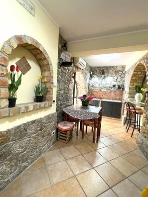 Un patio con pared de piedra, una mesa con sillas y un taburete pequeño.
