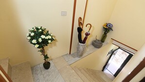 A staircase with a potted plant and a vase with flowers. - Al Vicoletto (Taormina)