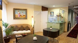 Un hall de hotel con un sofá, una mesa con un florero, una vitrina de cristal y una escalera.