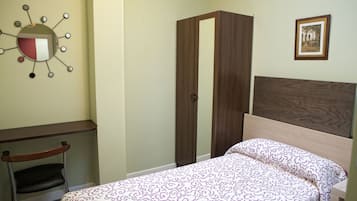 Una camera da letto con un letto, un armadio, una sedia e una lampada a parete.