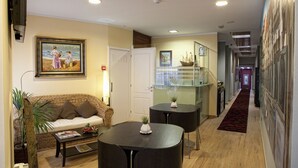 Una sala de estar con un sofá, una mesa de centro y dos mesitas auxiliares. En la pared hay un cuadro y una puerta que da a otra habitación.