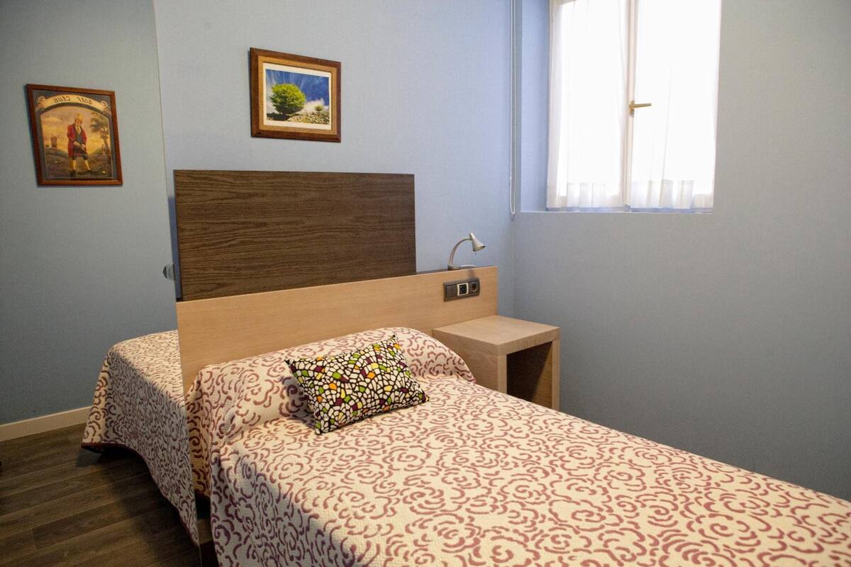 A bedroom with a bed, a nightstand, a lamp, and two framed pictures on the wall.