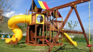 A wooden play structure with a slide and swing set.