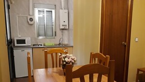 A compact kitchen with a microwave, a small refrigerator, and a window with blinds.