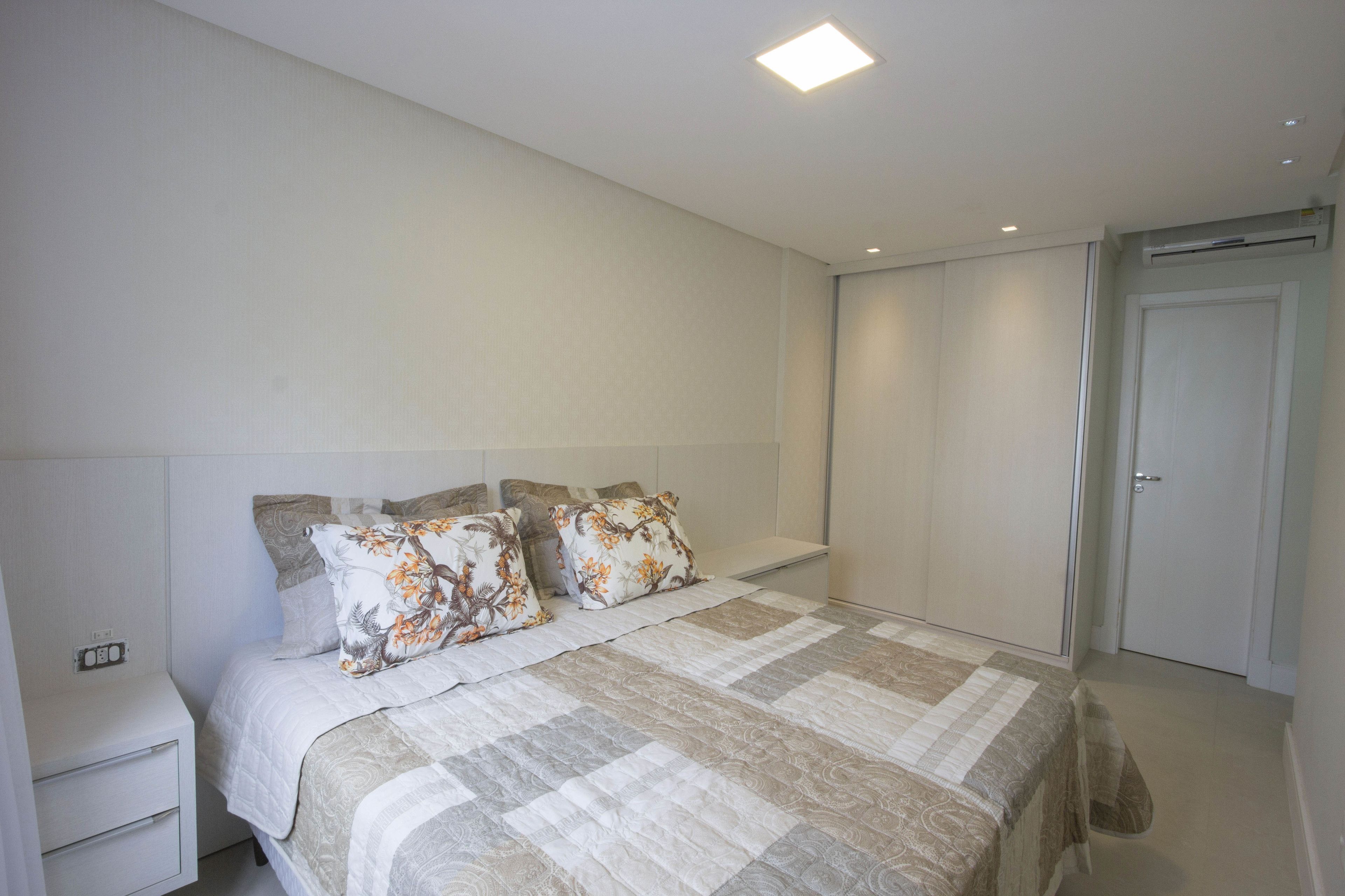 A bedroom with a large bed, a bedside table, a wardrobe, and a door.