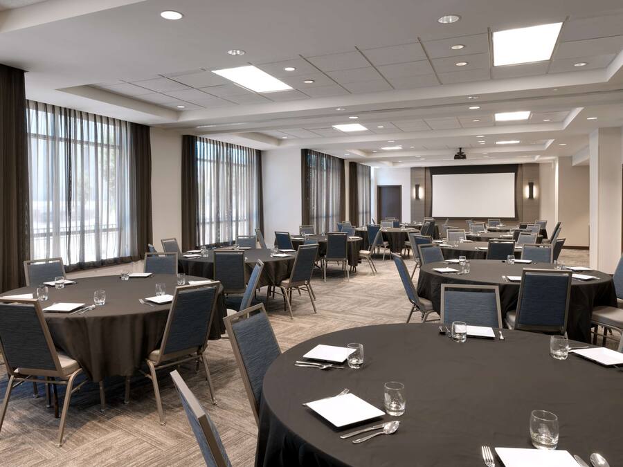 Une salle de conférence équipée de tables rondes, de chaises et d’un grand écran.