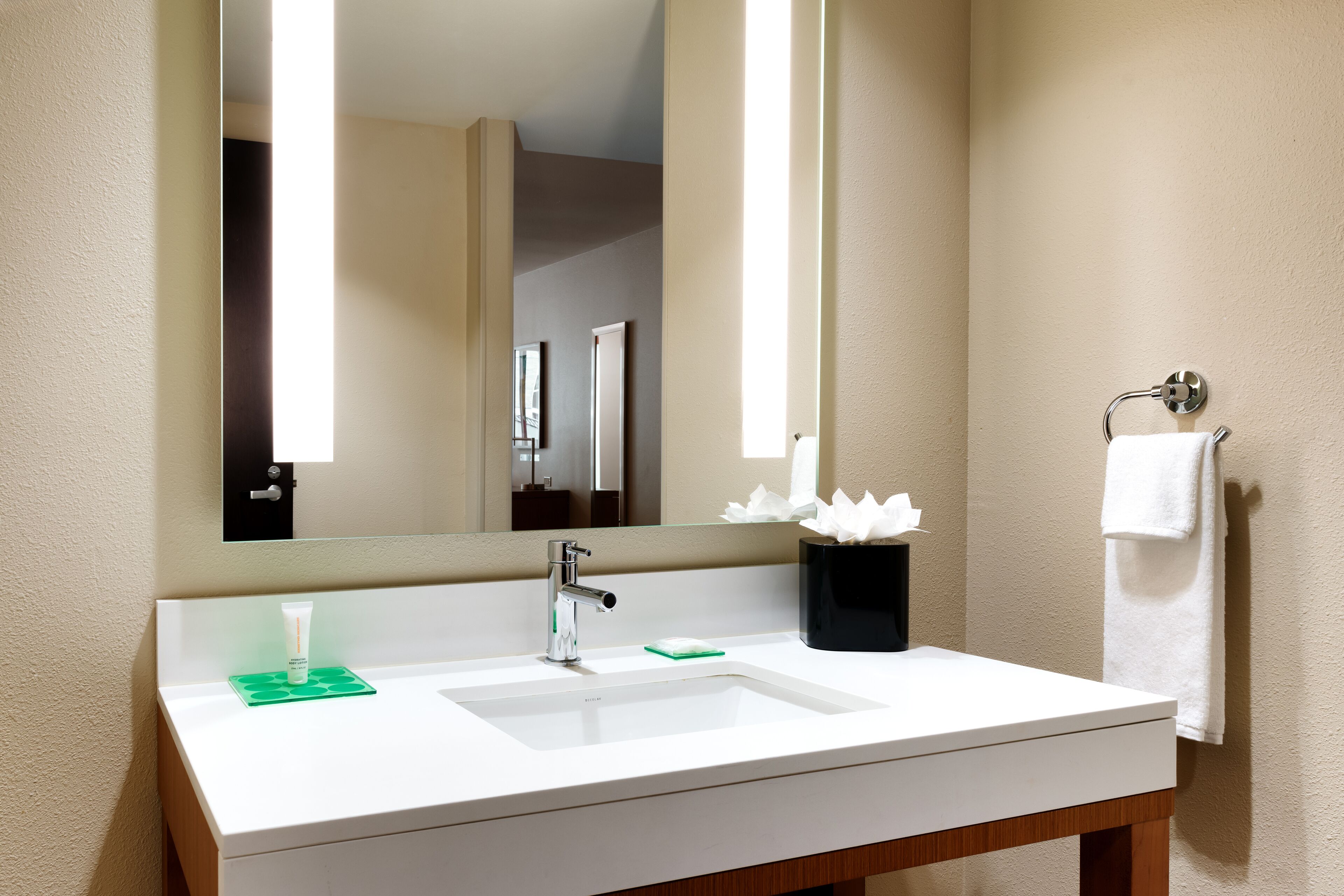 Une salle de bain avec un lavabo blanc, un miroir, un porte-serviettes et un porte-savon vert.