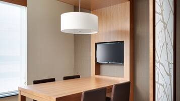 A conference room with a wooden table, chairs, a flat-screen TV, and a ceiling light fixture.