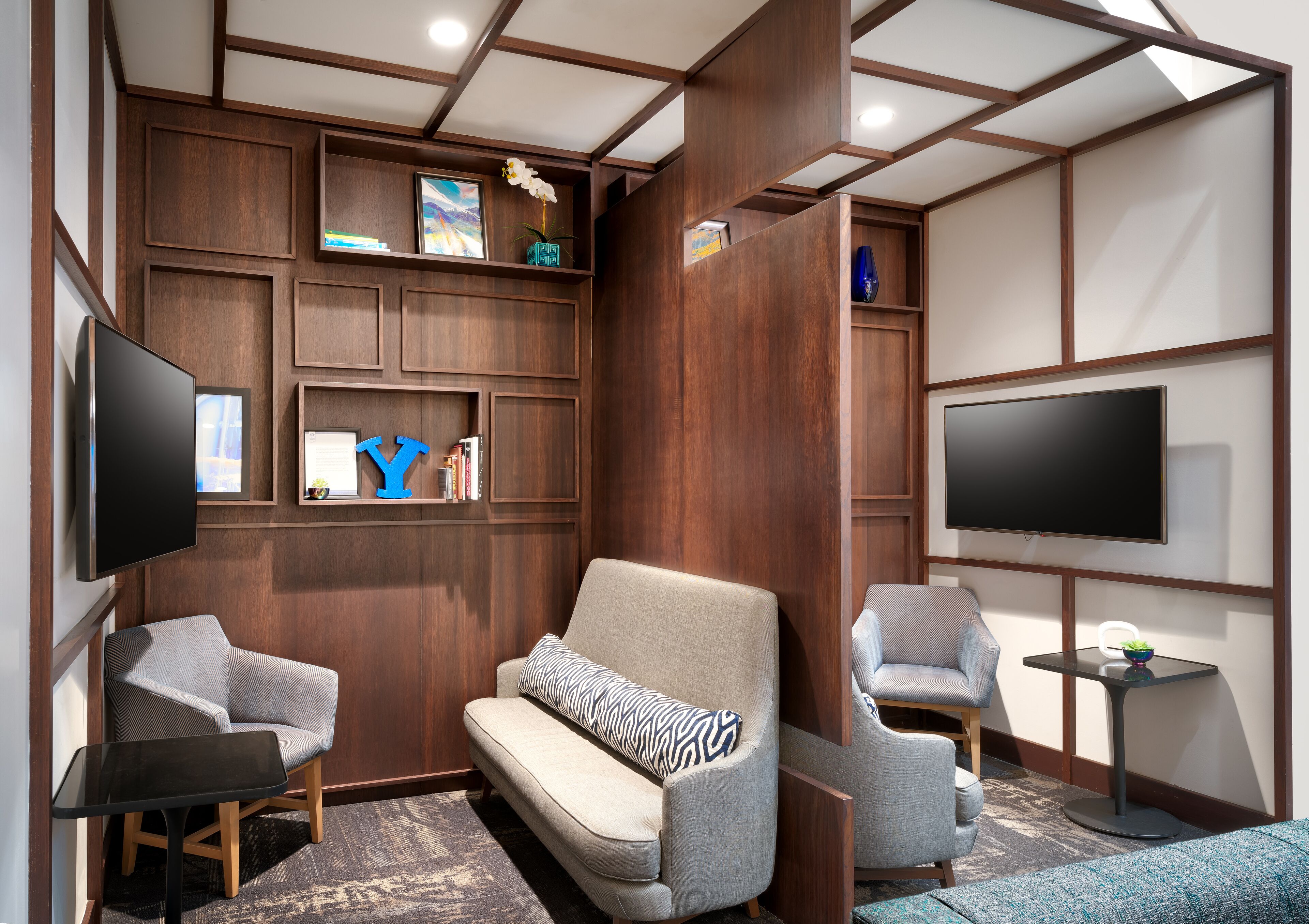 A modern living room with a sofa, armchairs, a TV, and built-in shelves with books and decorative items.