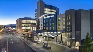Moderni hotelli, jonka yläpuolella on suuri, huomiota herättävä «Hyatt Place» -kyltti, ja jossa on katettu sisäänkäynti sekä valaistu kaupunkikatu hämärän aikaan.