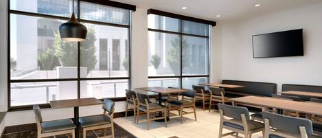 Un comedor moderno con ventanas amplias, mesas y sillas de madera.