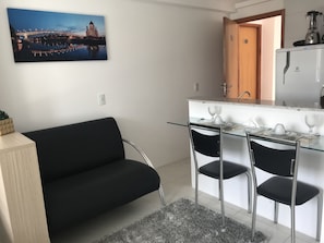 A modern kitchen with a glass dining table, two chairs, and a refrigerator.
