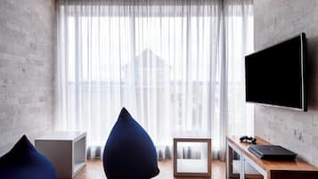 A modern living room with a large window, a flat-screen TV, and a wooden coffee table.