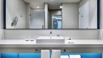 A modern bathroom with a large mirror, white sink, and two towels on a rack.