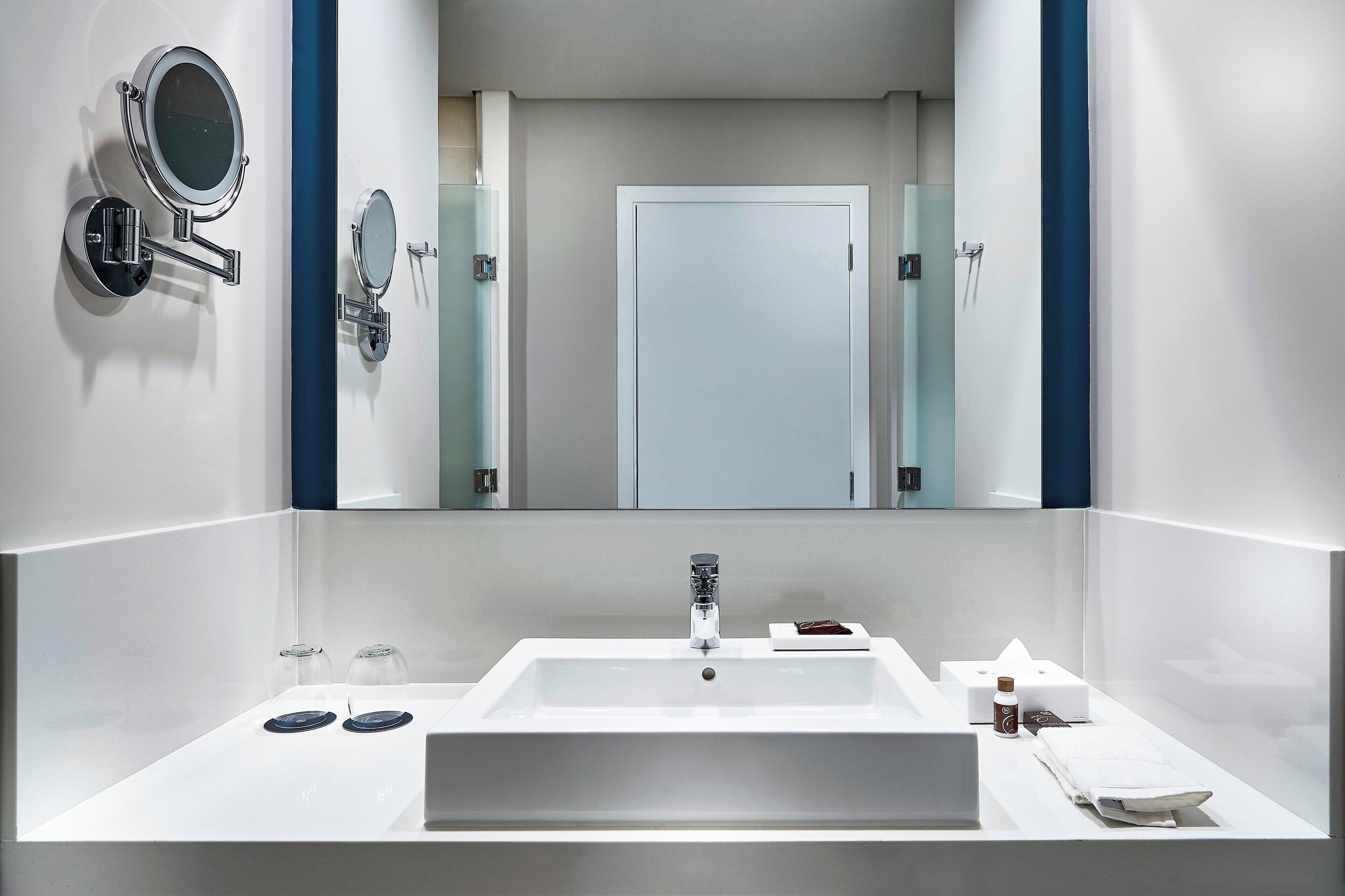 A modern bathroom with a large mirror, a sink, and a door.