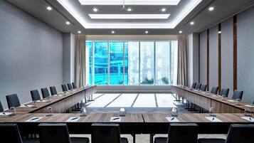 Ein Konferenzraum mit einem langen Tisch, Stühlen und einem großen Fenster mit Vorhängen.
