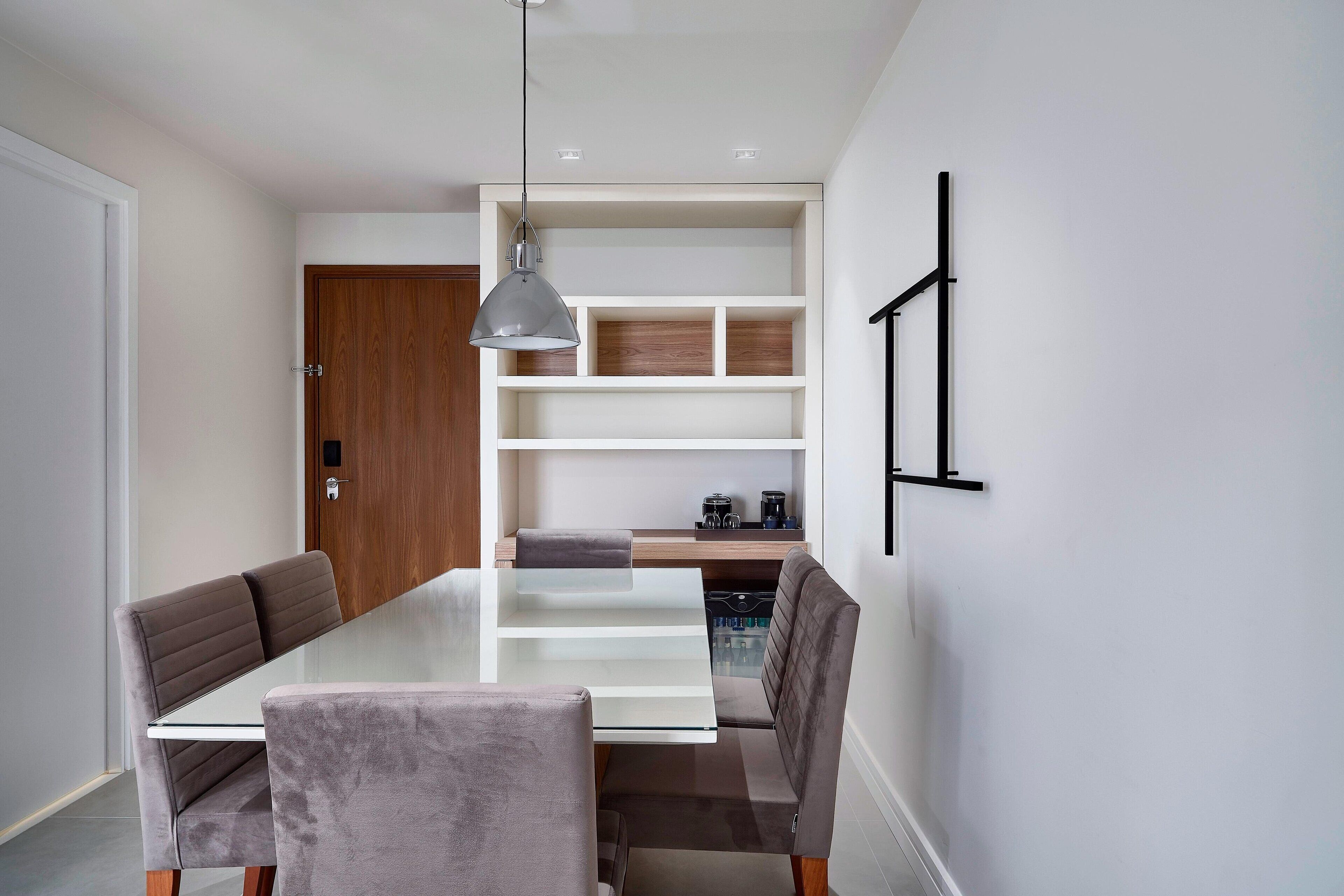 A modern dining area with a white table, grey upholstered chairs, and a pendant light.