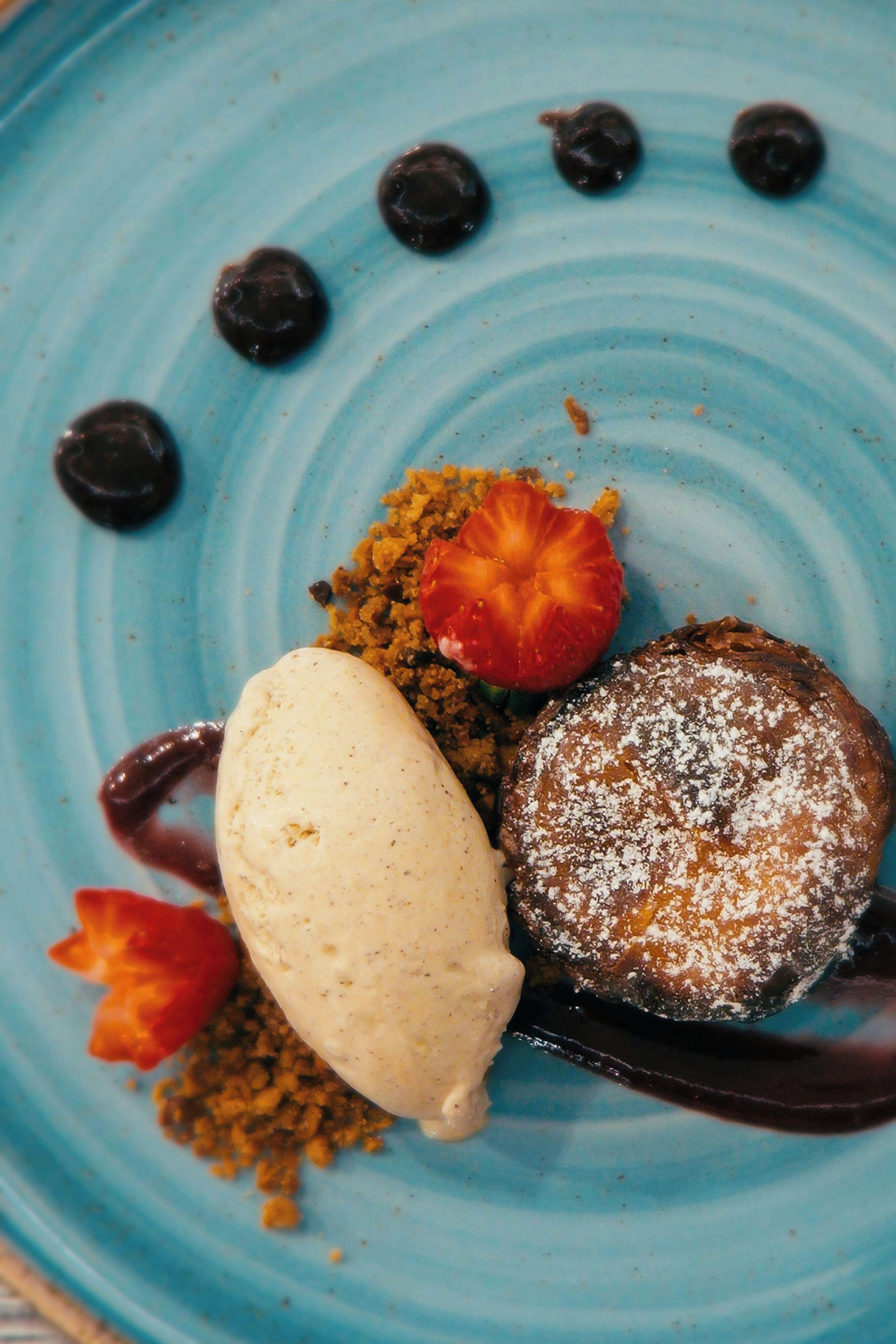 A dessert plate with a scoop of ice cream, a piece of cake, and a strawberry.