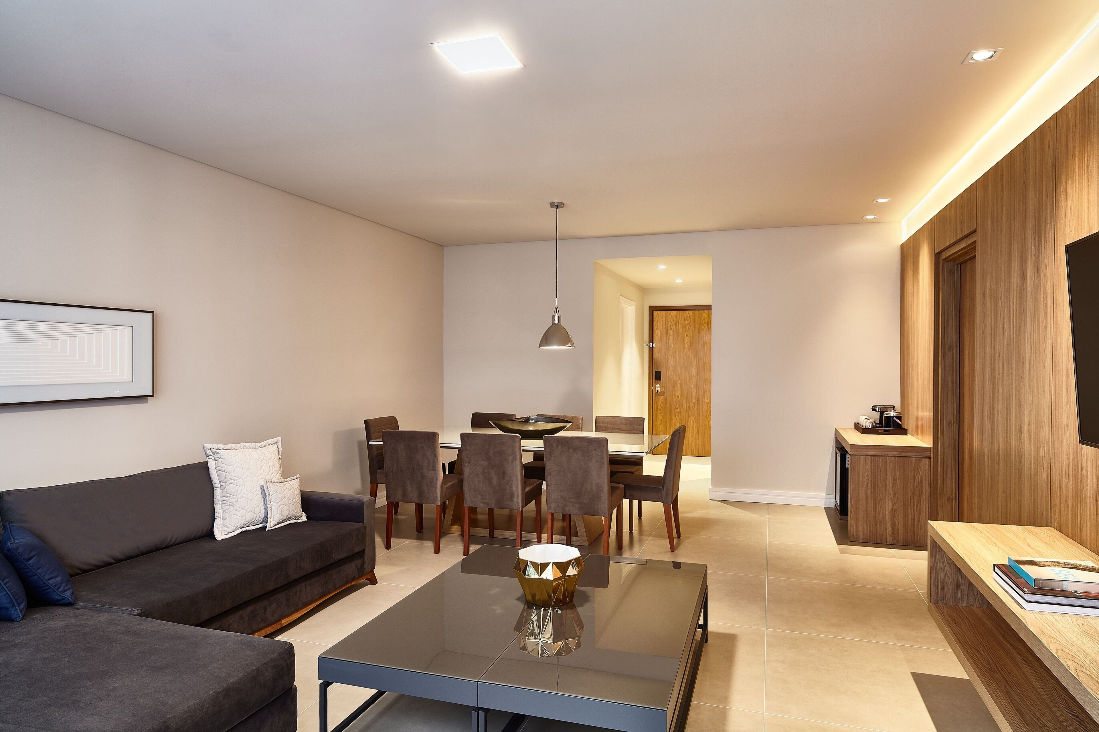 A modern living room with a sofa, a coffee table, and a dining area with chairs and a table.