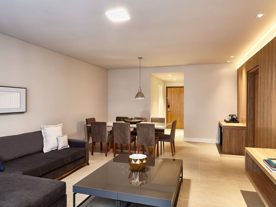 A modern living room with a sofa, a coffee table, and a dining area with chairs and a table.