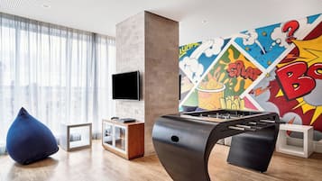 A modern living room with a foosball table, a flat-screen TV, and a colorful comic-style mural.