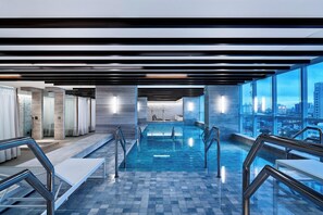 A modern indoor swimming pool with clear glass walls, metal railings, and a city view. - Sheraton Santos Hotel (Santos)