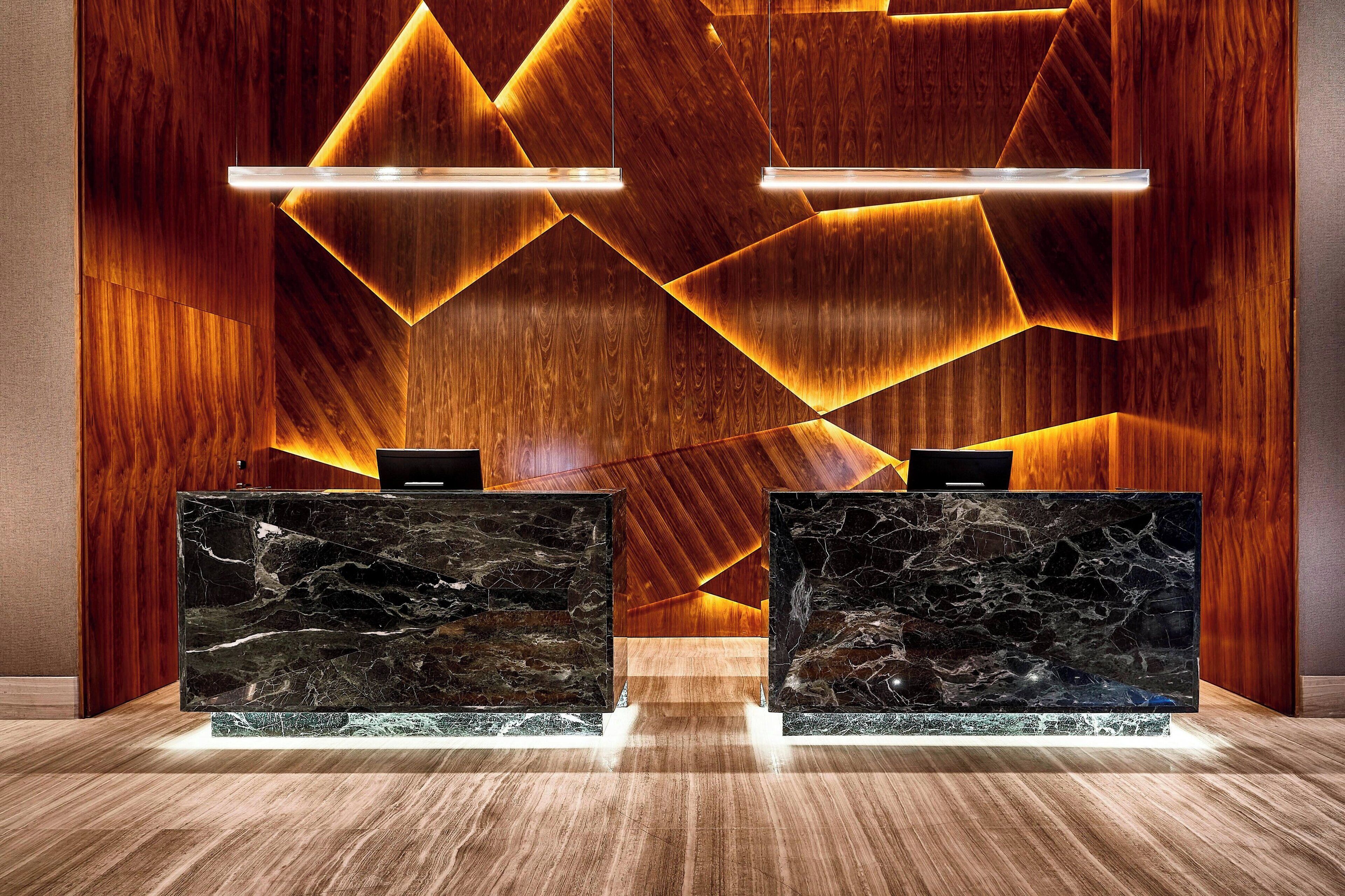 Una recepción con fondo de madera e iluminación geométrica.